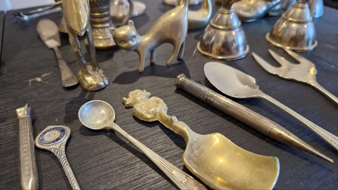 Dull, tarnished brass figurines and small spoons before cleaning
