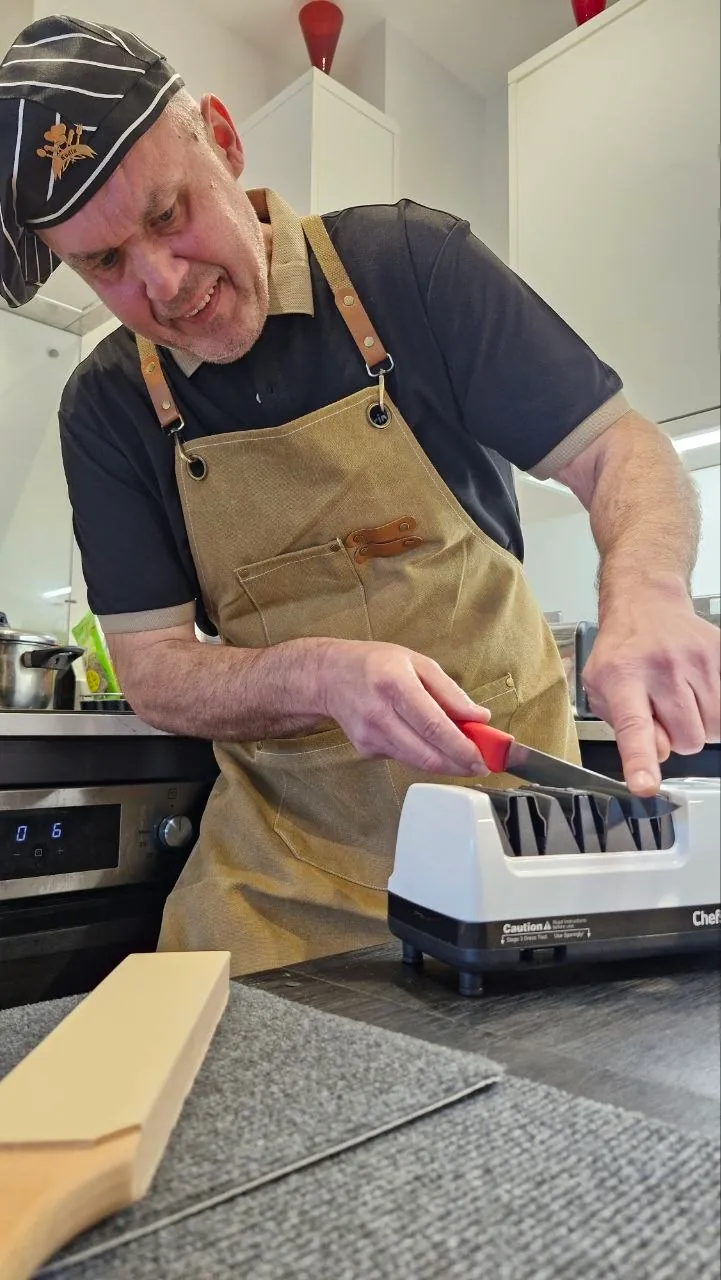 Volodymyr Kudin sharpening a kitchen knife on a professional sharpening machine